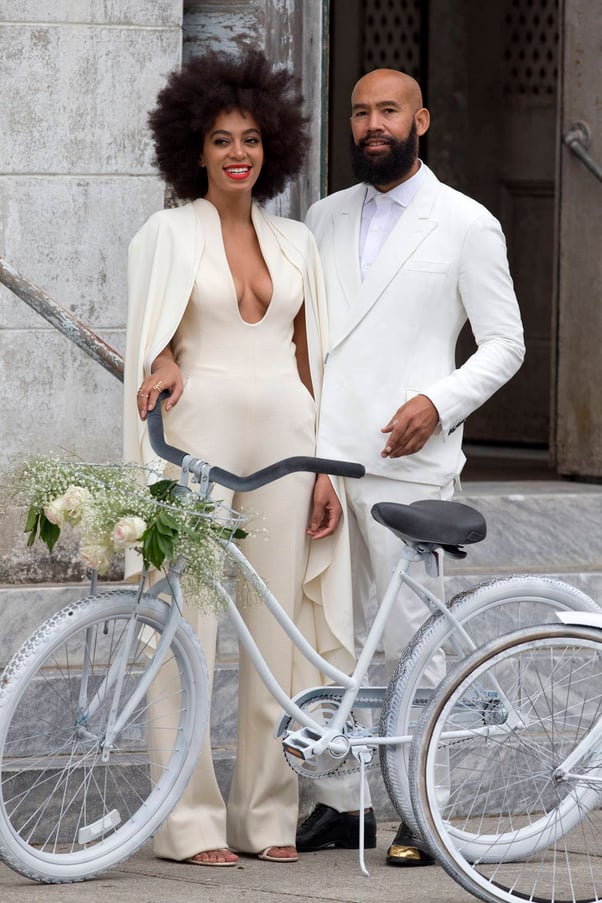 Solange Knowles and Alan Ferguson stand in all white clothes next to their white bike at their wedding.